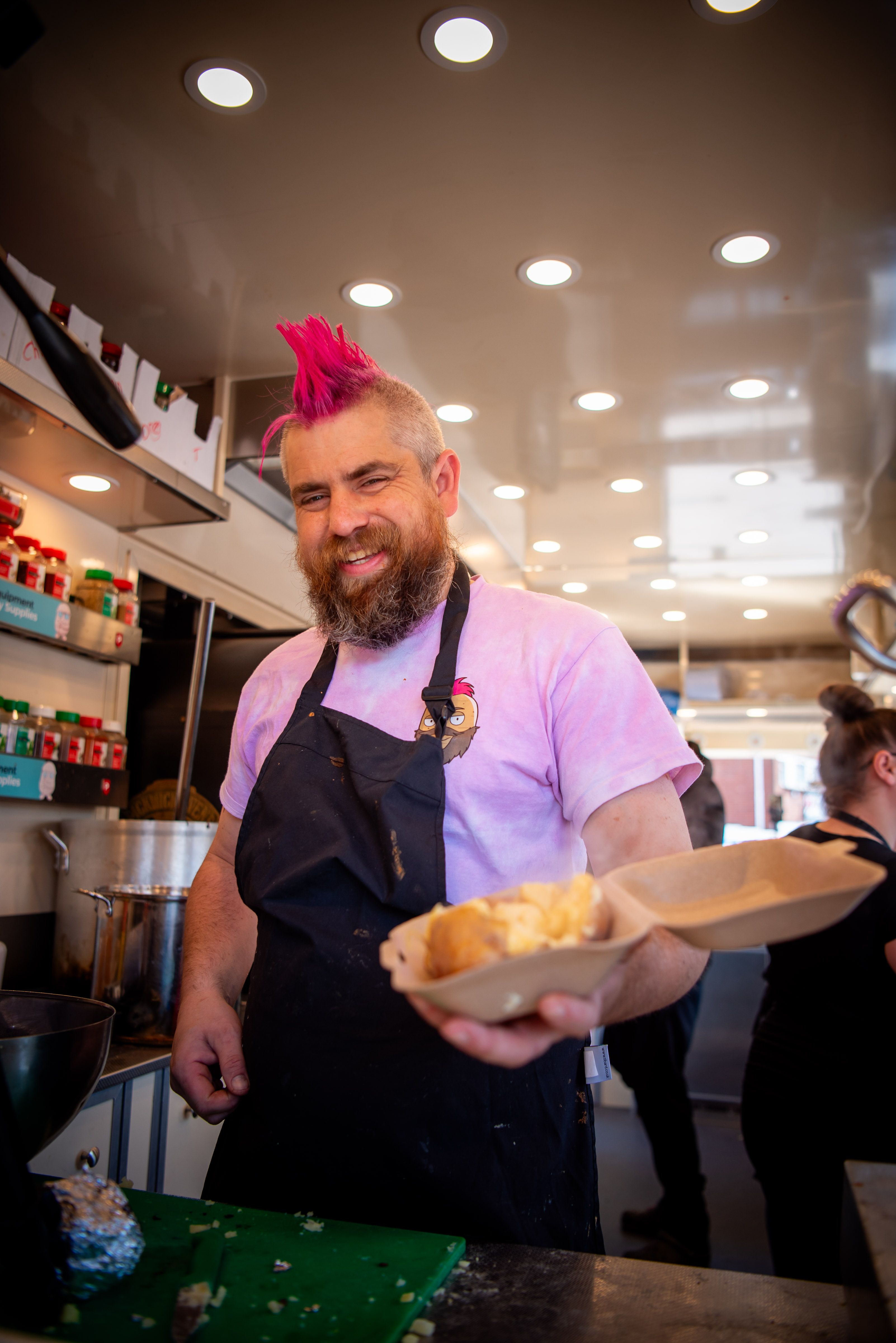 Photo of Ben Newman aka spudman holding a jacket potato in a container inside his spud van